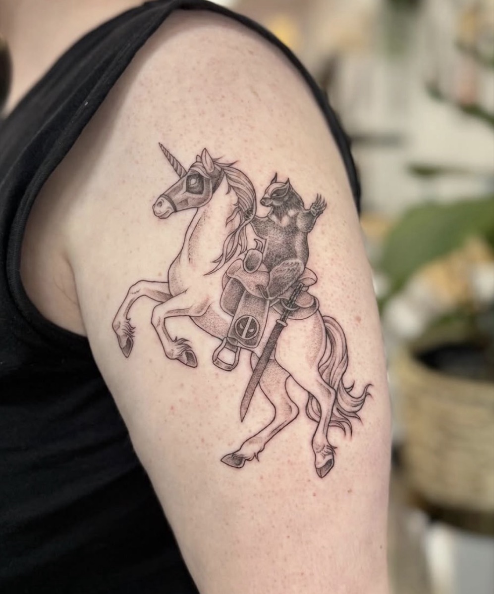 Raccoon riding a unicorn — whimsical fine line tattoo by Samantha Gunning